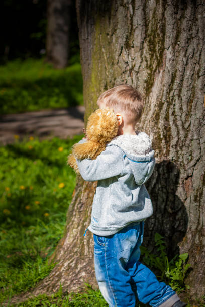 istock A cute boy is playing with a bear cub in the forest. The sun's rays envelop the space. A magical story of interactions for the book. Space for copying. 1407095181