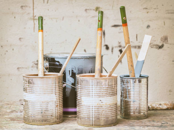 istock Used paint buckets and brushes in front of a stained wall 1407096307