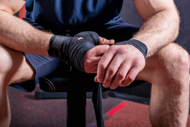 istock Hands of young and strong mixed martial arts fighter who wraps black protective elastic bandage around his fists 1407096616