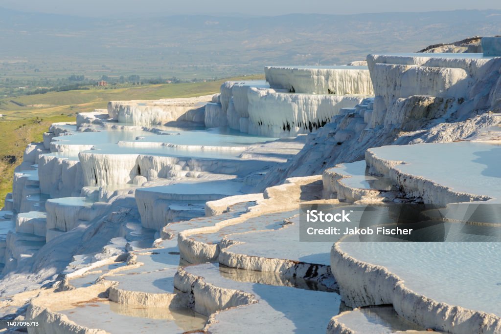 Travertine terrace, Pamukkale The enchanting pools of Pamukkale in Turkey. Pamukkale contains hot springs and travertines, terraces of carbonate minerals left by the flowing water. The site is a UNESCO World Heritage Site. Türkiye - Country Stock Photo