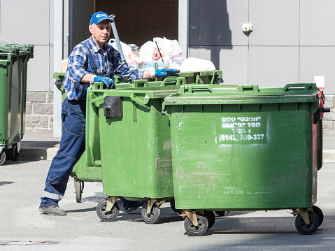 Petrozavodsk, Russia - 6 June 2022. refuse collection worker loading garbage for trash removal