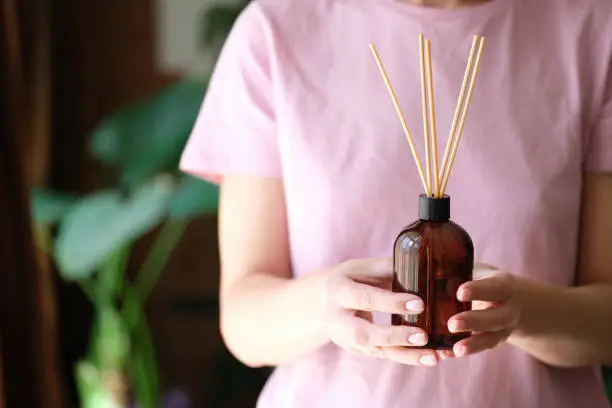 Person holds bottle of incense and aromatherapy incense sticks. Essential oils concept