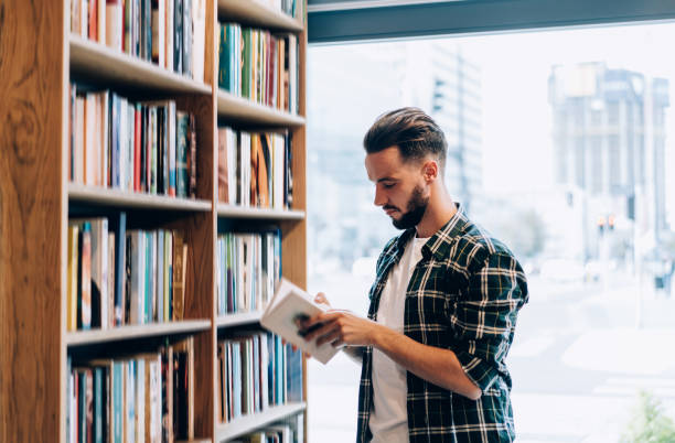 istock Serious male student choosing textbook in modern library 1407097767