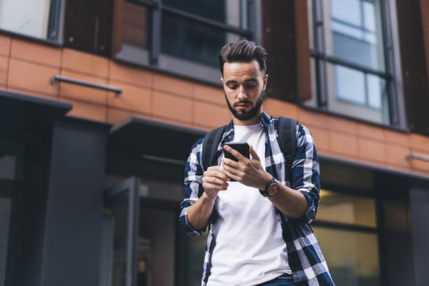istock Serious man using smartphone on street near modern building 1407097843