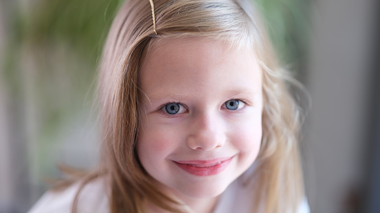 11-year-old girl with blue eyes and pigtails wearing cream-colored clothes.