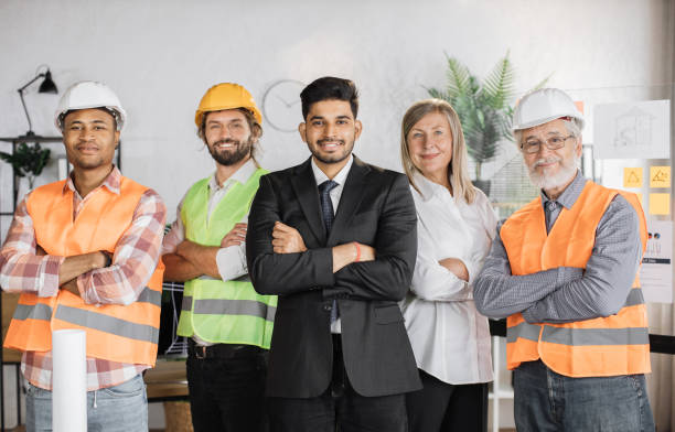 istock Front view of builders, architects looking at camera while standing on light modern office. 1407098647
