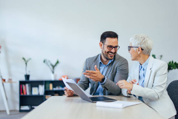 istock Smiling businessman talking to his colleague, holding some papers, explaining something. 1407098847