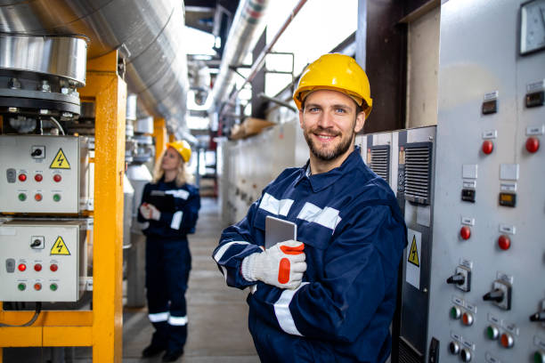 Portrait of an industrial electric engineer standing by power supply inside oil refinery. stock photo
