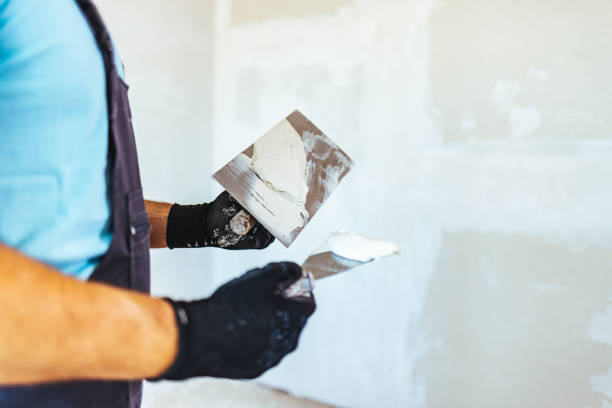 Plastering a wall Handsome construction worker finishing a facade of interior wall, wall renovation stock pictures, royalty-free photos & images