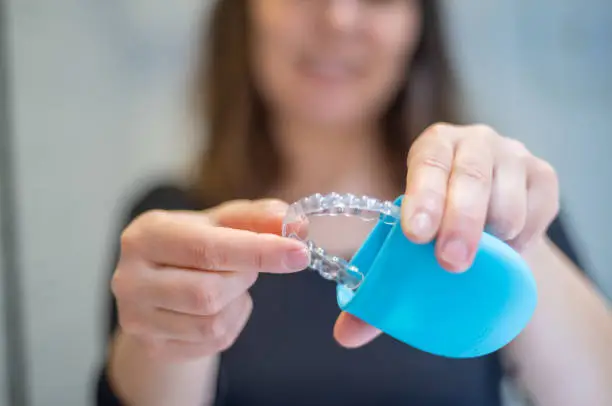 Woman Storing her dental aligner is a blue case after use