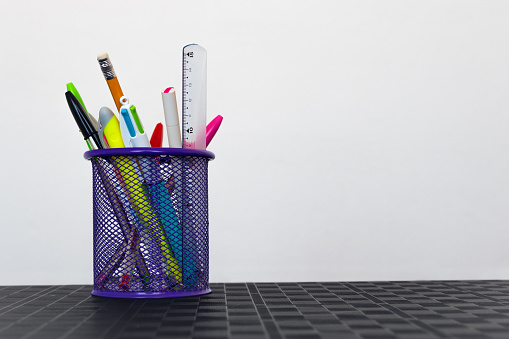 Several school supplies in a pen holder on the office desk isolated on white background with empty space for text on the right