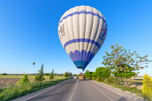 Cappadocia, Turkey- May 29, 2022: A hot air balloon lands on a road where cars are driving