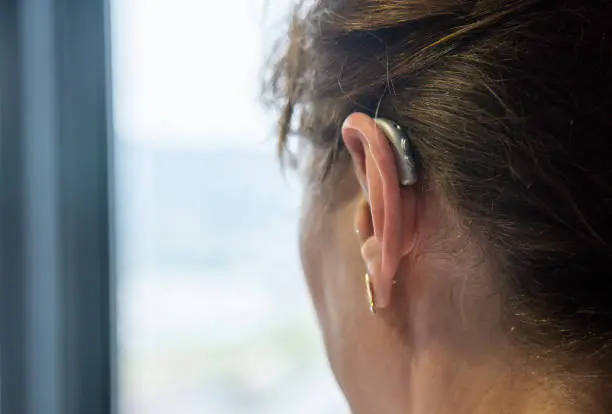Woman placing hearing aid on her right ear