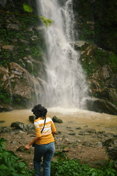 Woman walking toward a majestic waterfall at Pelling, Sikkim