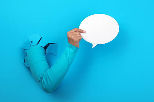 Talk bubble speech icon in hand over blue background