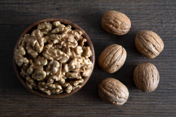 istock Peeled walnuts and whole walnuts on wooden background 1407106883