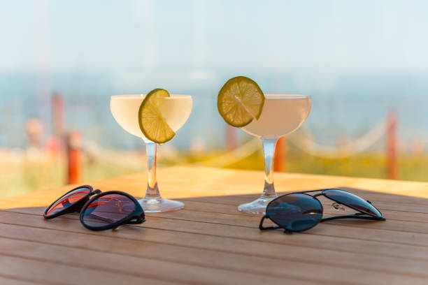 dois copos de margarita. conceito de bar de praia. coquetéis alcoólicas de verão, óculos de sol no bar de mesa, mar ao fundo. - 13601 - fotografias e filmes do acervo