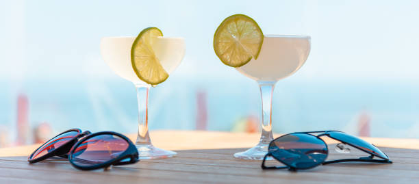 fresh cold tasty two margarita cocktails with lime and ice,lying sunglasses on a table.beach bar concept.summer alcoholic cocktails on table bar, sea on background.banner,advertisement. - 13603 imagens e fotografias de stock