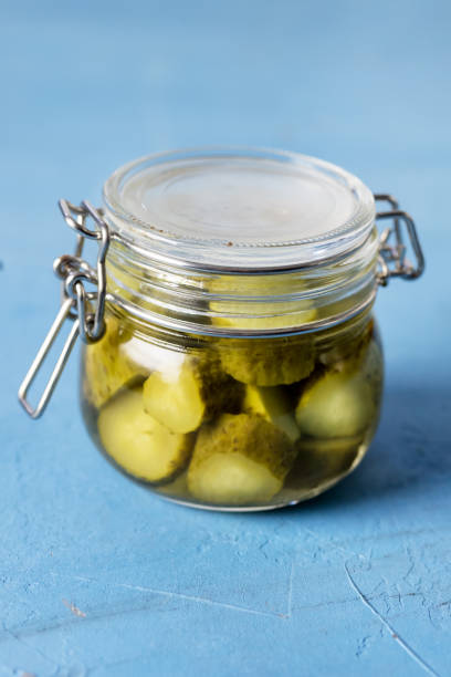istock Homemade Marinated Cucumbers with Spices in a Glass Jar on Blue Background Vertical 1407108859