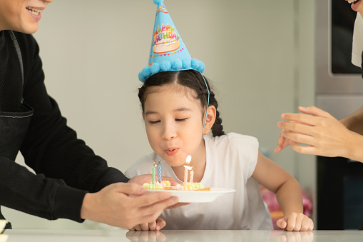 New generation asian family cook together and organize a small birthday party for our little daughter in the kitchen of the house