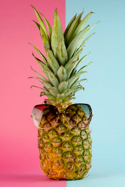 istock Pineapple with sunglasses. Summer vacation concept on pink and blue background 1407111773