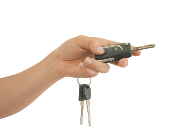 istock Male hand holds a black car key isolated on white background with clipping path. 1407113820