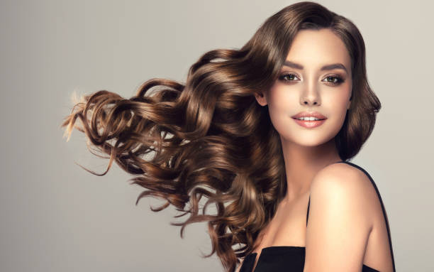 joven, hermosa modelo de cabello castaño con cabello largo, ondulado y bien arreglado. excelentes ondas capilares. arte de peluquería y cuidado del cabello. - cabello humano fotografías e imágenes de stock