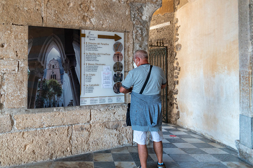 Amalfi is a town and a comune in the province of Salerno, in the Campania region, as a part of the Amalfi Coast, it was declared a World Heritage site by UNESCO on September 2021. Tourist reading information at Saint Andrew`s Cathedral.
