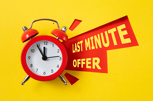 Red alarm clock with colored papers and last minute offer text on yellow background