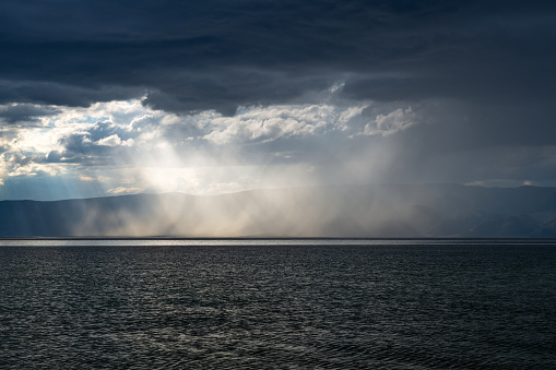 Sun rays are shining through  clouds  to lake.  Baikal lake on Olkhon island. Sky after rain.