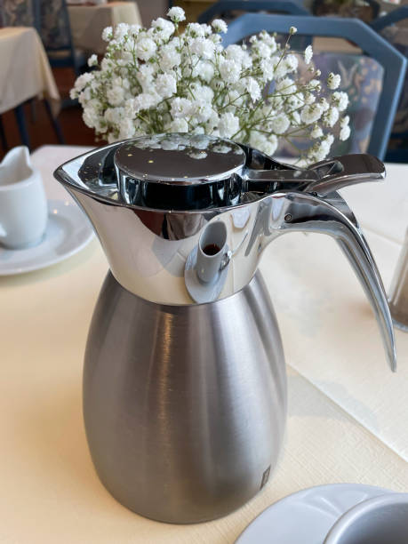 Metal coffee pot on a table in a cafe.