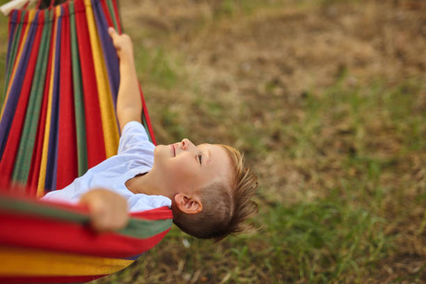istock Cute boy is sitting in a hammock. 1407121320