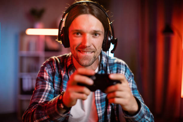 istock Portrait of cheerful caucasian guy in headset using remote console for playing video games at home 1407121404