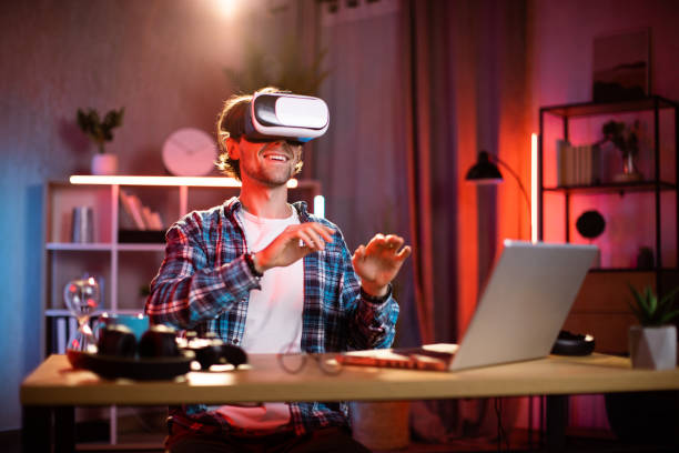 istock Positive caucasian man using wireless virtual reality glasses while working remotely at home. 1407121413