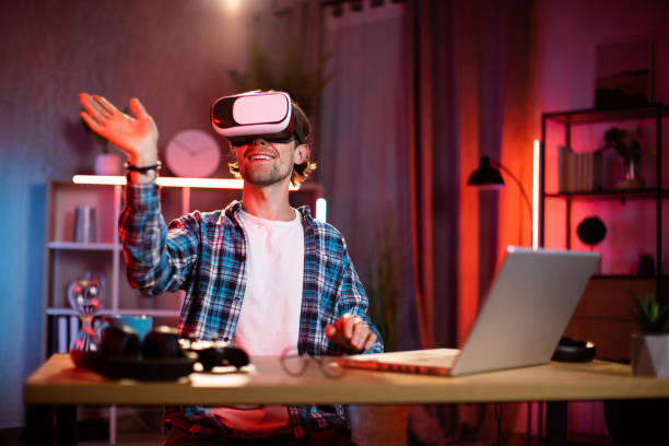 istock Young caucasian man sitting at home office and using VR glasses and laptop for remote work. 1407121421