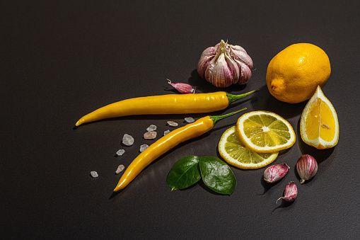 Cooking ingredients background. Spices, vegetables, garlic, yellow peppers chili. Black background, preparation food concept, flat lay, hard light, dark shadow, copy space