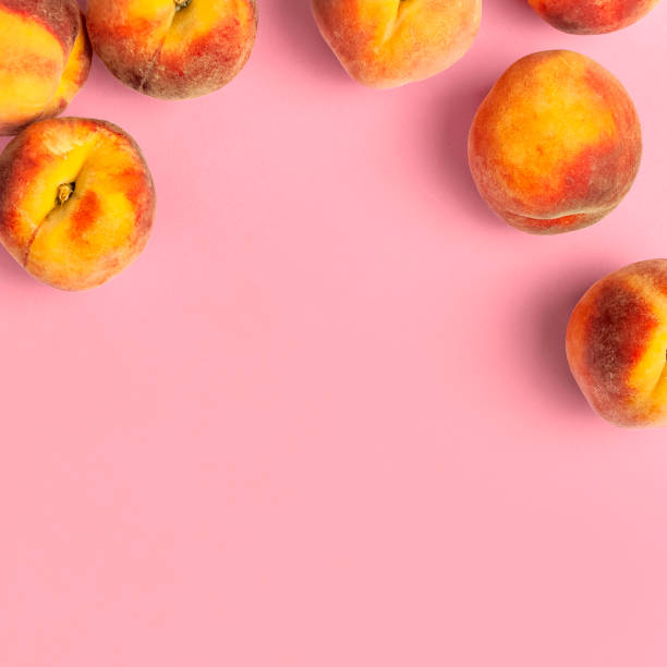 Ripe juicy peaches with green leaves on pink background. Flat lay, top view, copy space. Minimal creative composition with peaches. Fresh organic fruit, vegan food. Harvest concept