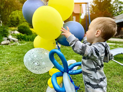 Toddler boy playing with balloons outdoors. A cute boy of one and a half years. Selective focus