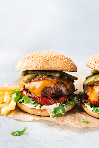 Delicious craft cheeseburgers with arugula, roasted bell pepper and pickles. Copy space