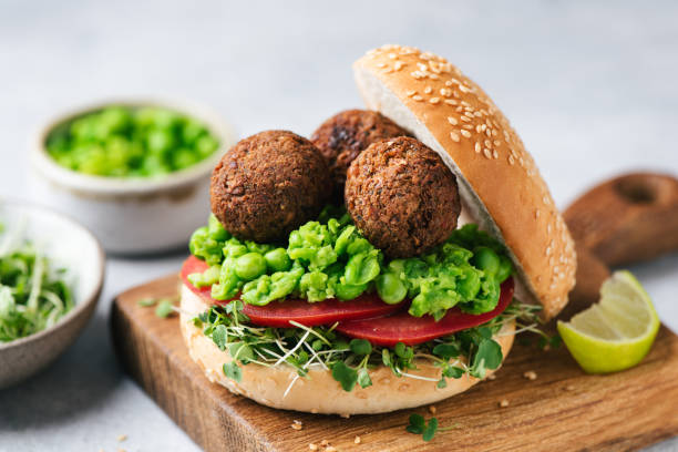 Plant based falafel burger with vegan green pea sauce and tomatoes stock photo