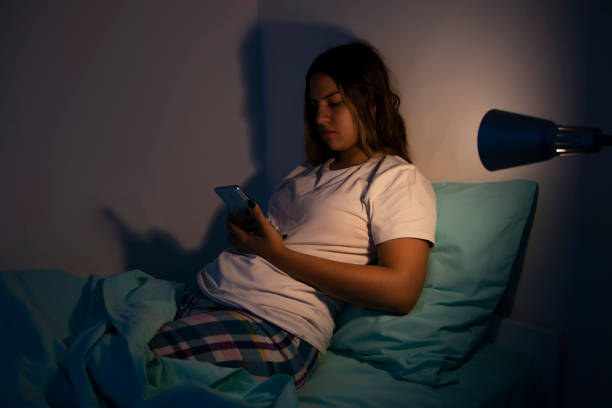 portrait of beautiful teen girl lying on bed and typing message on mobile phone. - homework teenager mobile phone school imagens e fotografias de stock