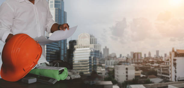 istock Engineer holding a sheet of construction structure drawing to a construction site 1407130789