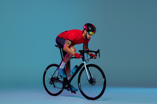Wheelman. Studio shot of professional cyclist in red sports uniform, goggles and a helmet on a blue background. Concept of active life, rest, travel, energy, sport. Copy space for ad