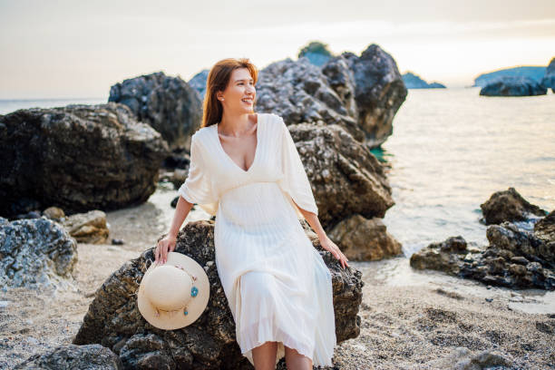 istock Young woman on the rocky beach during sunset 1407131745