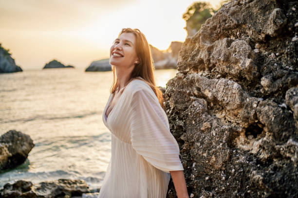 istock Young woman on the rocky beach during sunset 1407131811