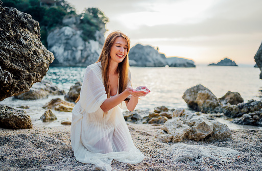 Young smiling woman holding pebble stones from the beach