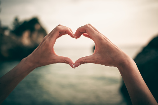 Woman hands making hart shape on the beach