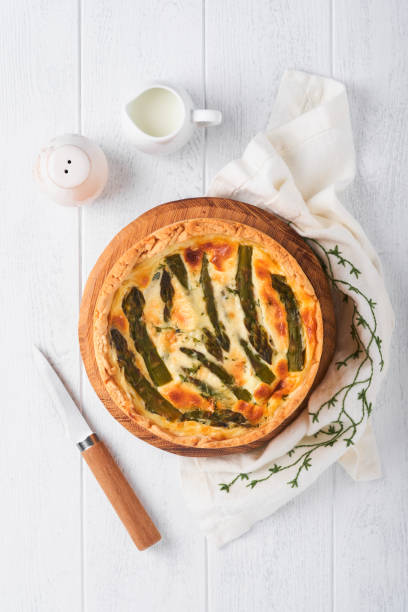 istock Quiche. Homemade asparagus pie or quiche with cheese and spinach on white wooden table background. Traditional French Quiche. Top view. 1407132191