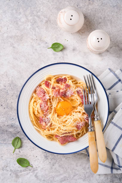 istock Carbonara pasta. Spaghetti with pancetta, egg, parmesan cheese and cream sauce on old gray concrete table background. Traditional italian cuisine and dish. Pasta alla carbonara. Top view. 1407132457