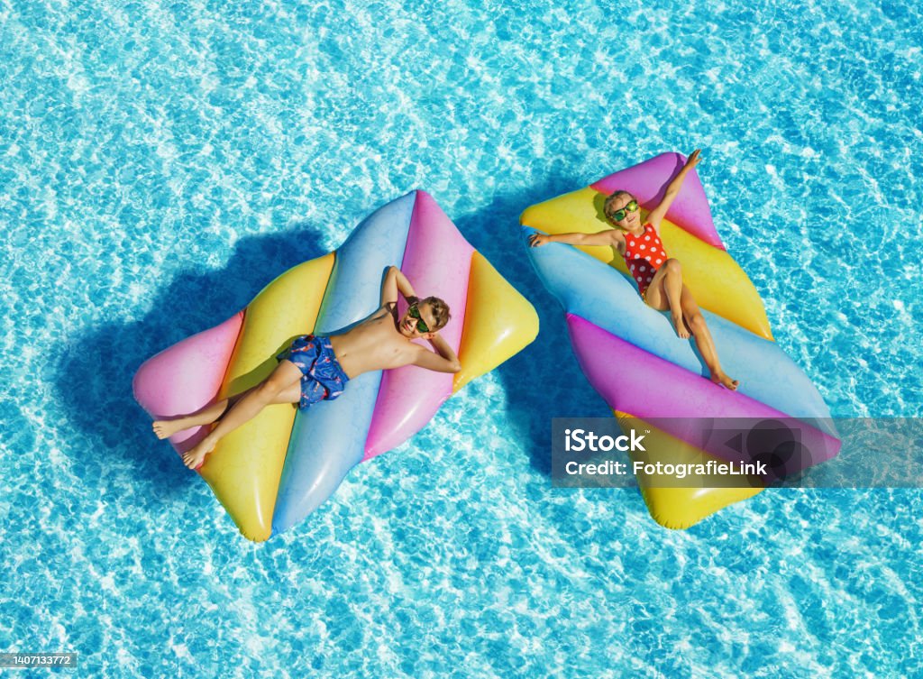 Funny children On Inflatable Swimming Mattress In Pool Family Stock Photo